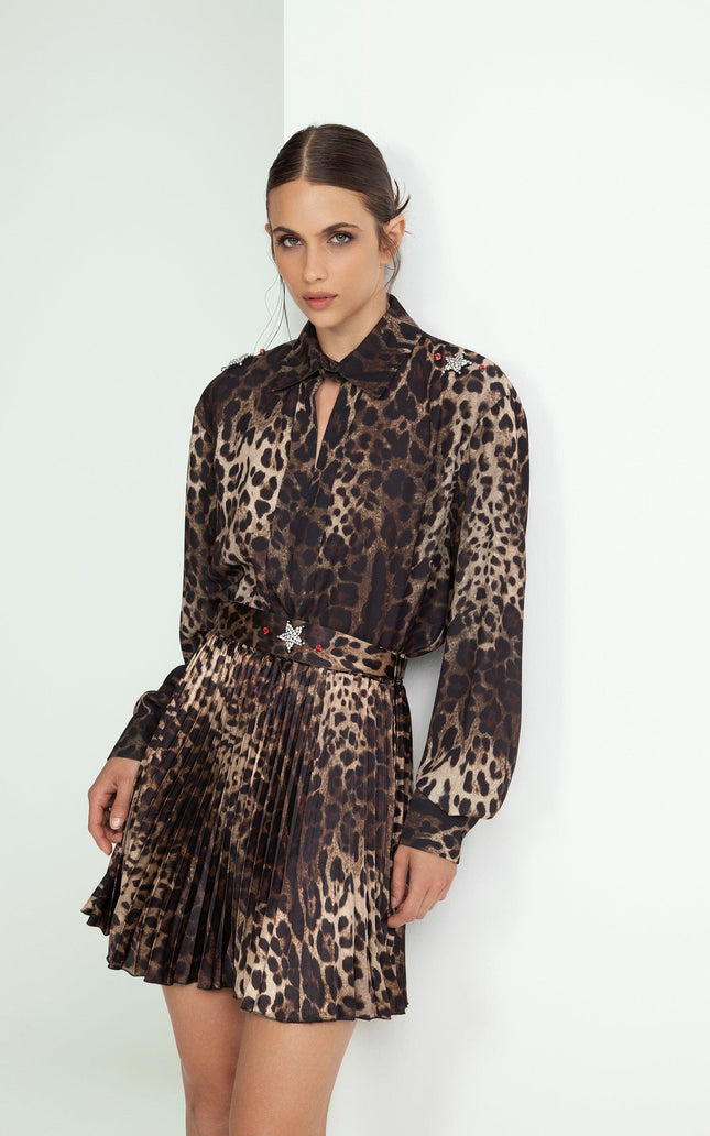 Woman wearing a pleated leopard print dress with long sleeves and a belted waist
