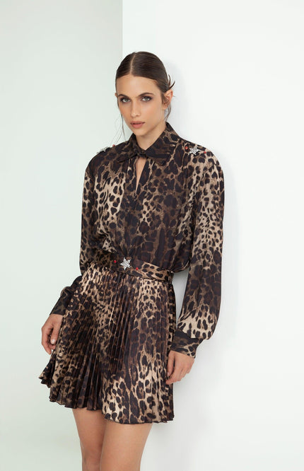 Woman wearing a pleated leopard print dress with long sleeves and a belted waist