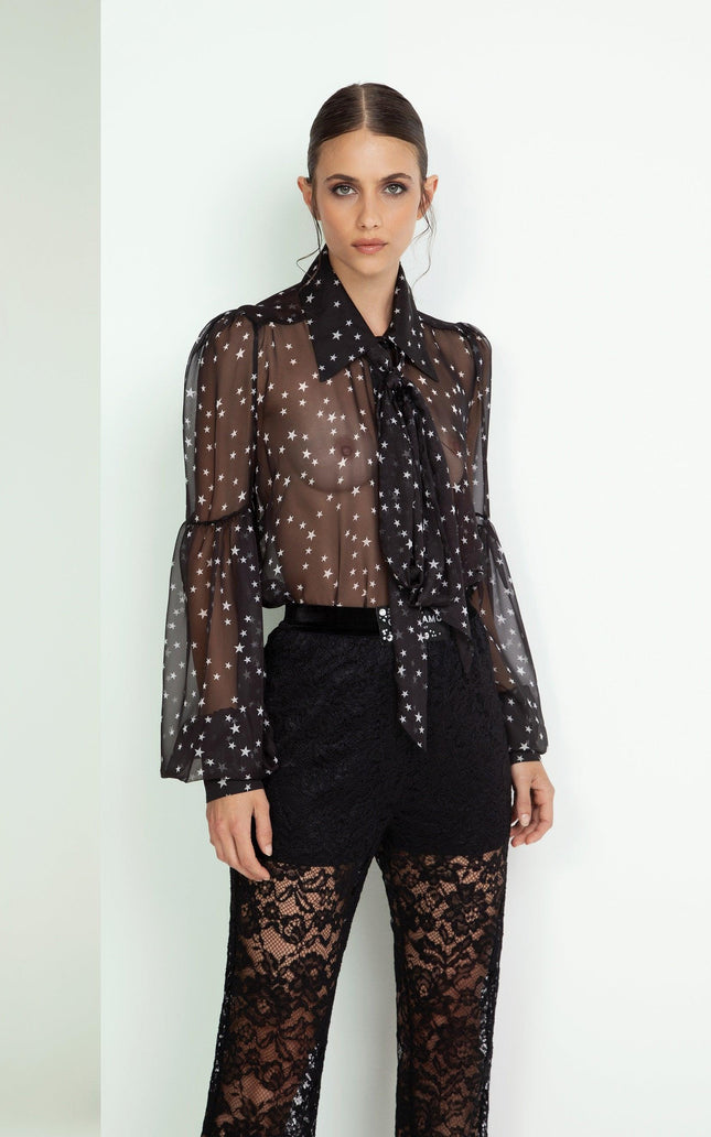 Woman wearing sheer black star print blouse and black lace pants, modern fashion look