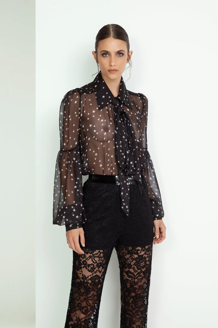 Woman wearing sheer black star print blouse and black lace pants, modern fashion look