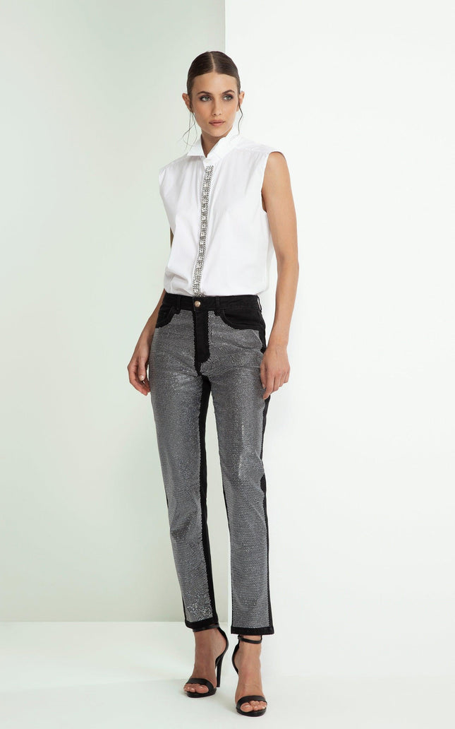 Woman in sleeveless white shirt with jeweled trim and metallic pattern pants, fashion look