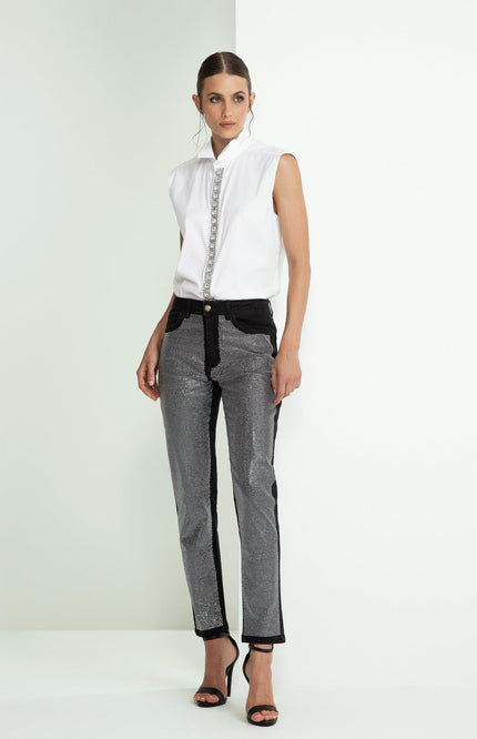 Woman in sleeveless white shirt with jeweled trim and metallic pattern pants, fashion look
