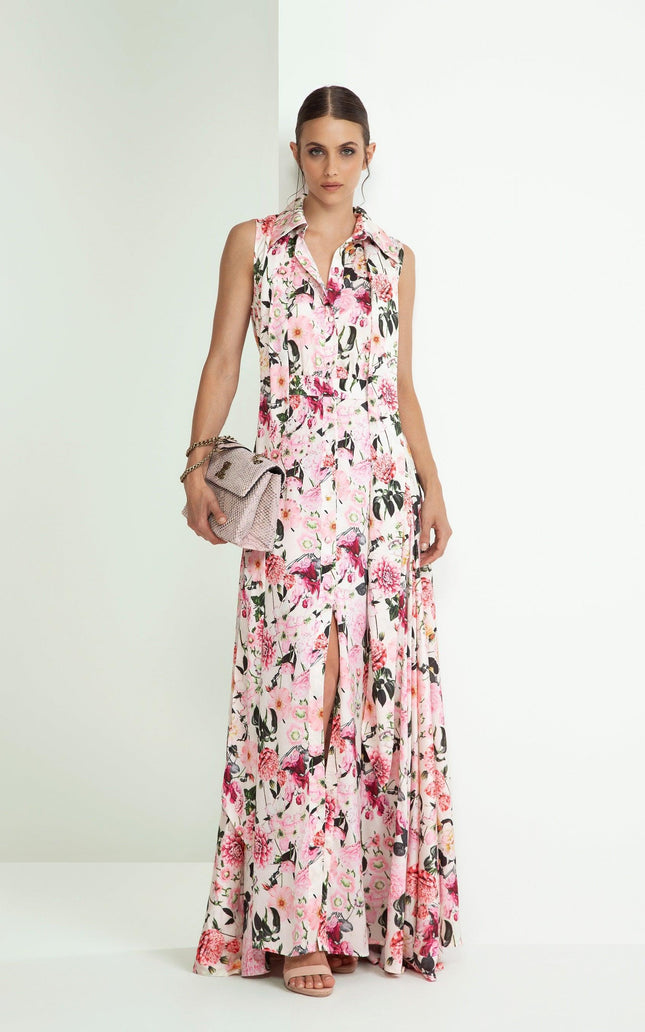 Woman wearing sleeveless floral maxi dress with front slit, holding textured clutch