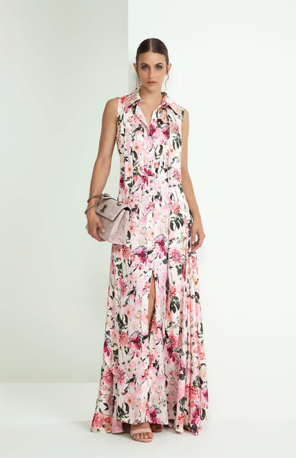 Woman wearing sleeveless floral maxi dress with front slit, holding textured clutch