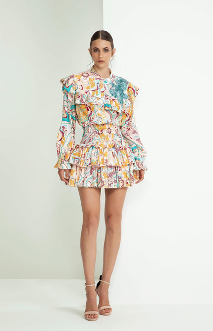 Woman wearing a colorful ruffled mini dress with long sleeves and floral print