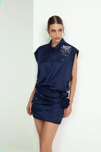 Woman wearing navy blue short dress with sequin details and floral accents, fashion photography