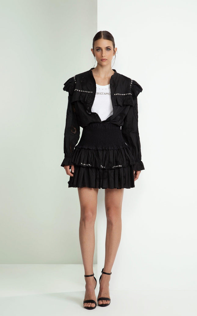 Woman in black ruffled mini skirt, white graphic tee, and black studded jacket
