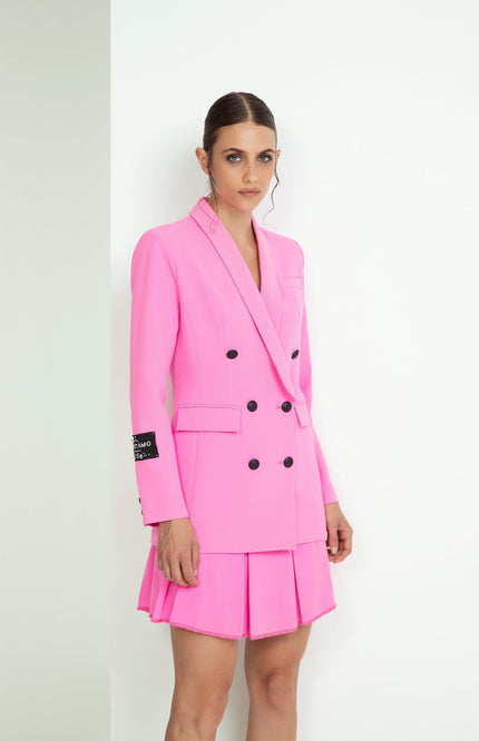 Woman wearing a pink double-breasted blazer dress with pleated skirt and black buttons