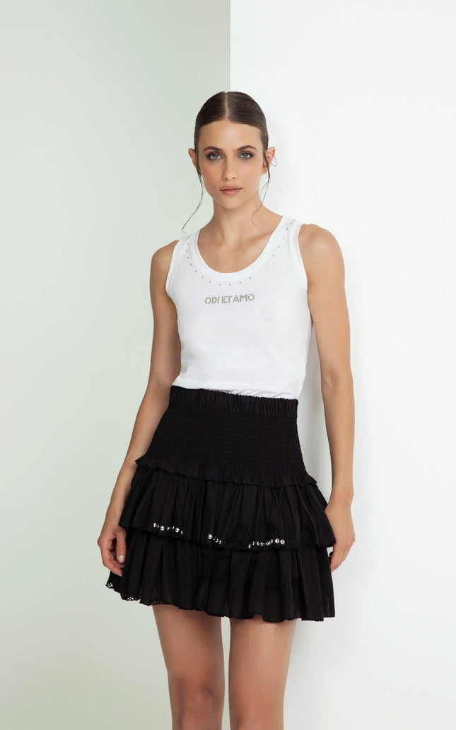 Woman in white sleeveless studded tank top and black ruffle mini skirt with pearls