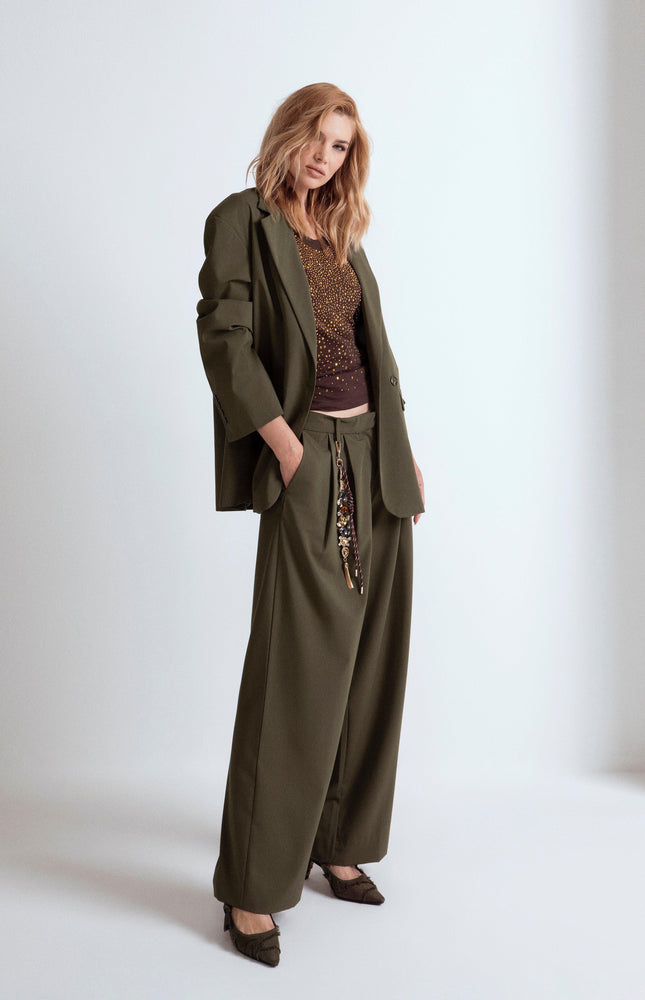 Donna indossa blazer oversize verde scuro con pantaloni larghi.