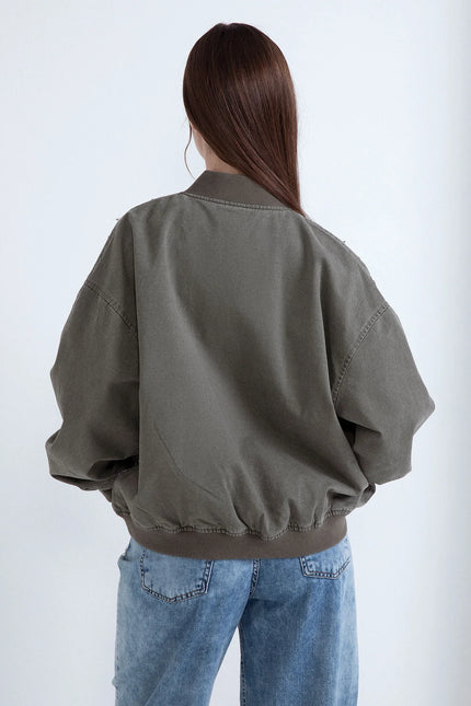 Gemini said
Donna di spalle con bomber verde militare dal taglio oversize e jeans azzurri su sfondo bianco