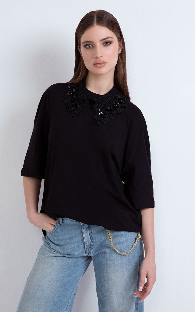Front view of a woman showcasing the oversized black version of the cotton T-shirt featuring a matching black macramé lace neckline.