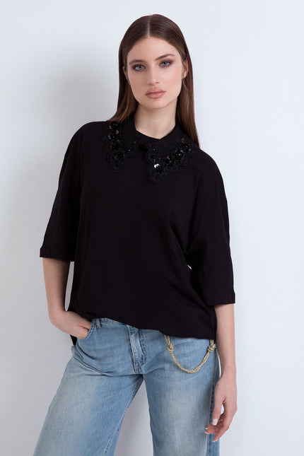 Front view of a woman showcasing the oversized black version of the cotton T-shirt featuring a matching black macramé lace neckline.