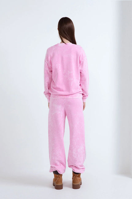 Vista posteriore di una modella in tuta rosa effetto lavato e scarponcini scamosciati marroni.