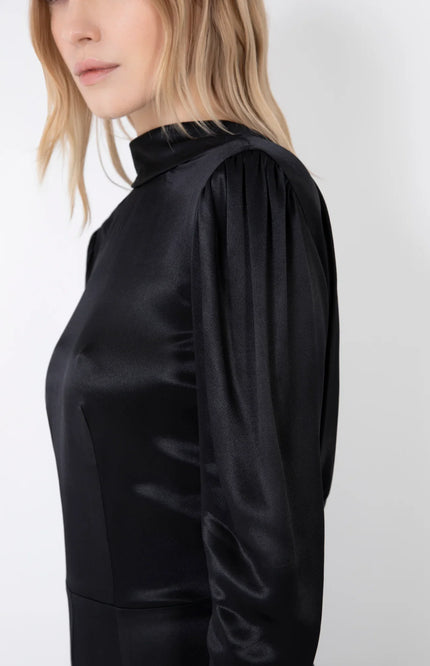 Woman wearing long sleeve black satin dress with gathered shoulders and high neckline