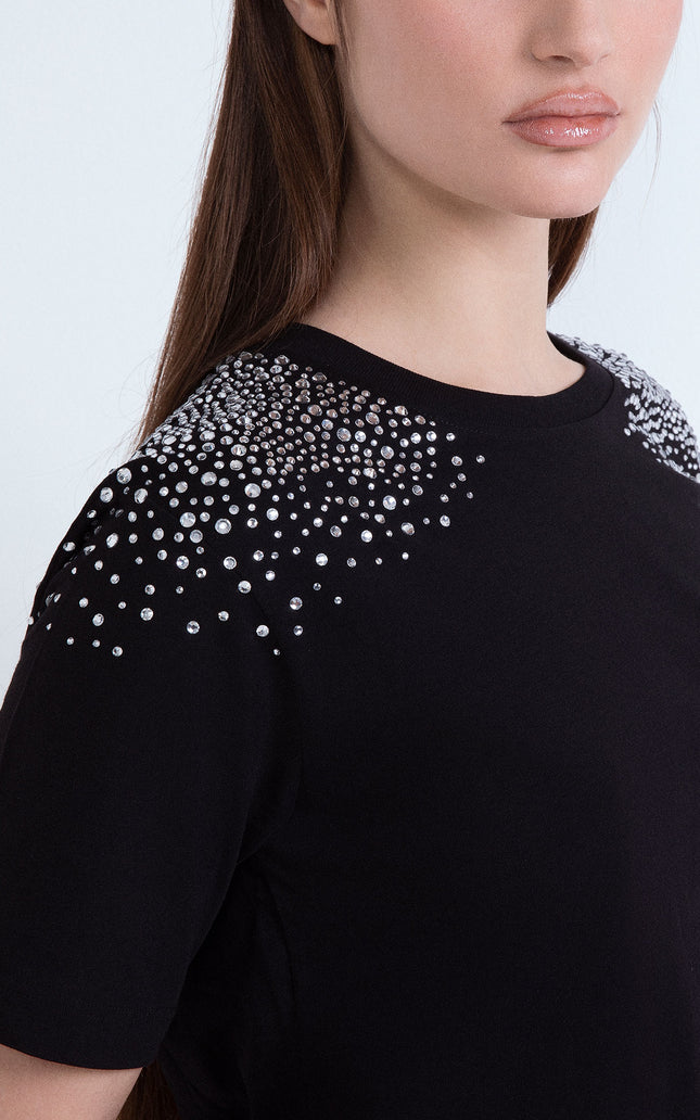 Maglietta nera da donna con dettagli di cristalli luminosi applicati sulle spalle.