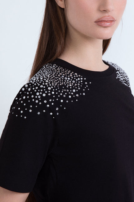 Maglietta nera da donna con dettagli di cristalli luminosi applicati sulle spalle.