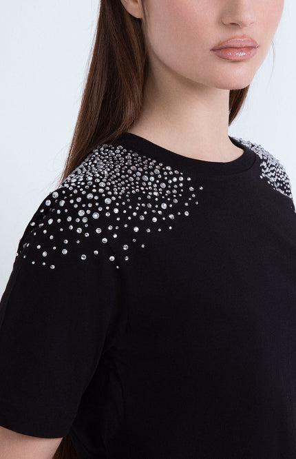 Maglietta nera da donna con dettagli di cristalli luminosi applicati sulle spalle.