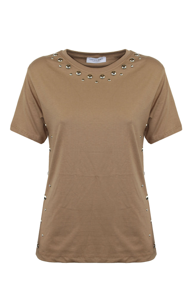 Modella che indossa la t-shirt color cammello firmata ODI ET AMO con profili decorati da borchie dorate, abbinata a una gonna nera con frange e stivali da cowboy