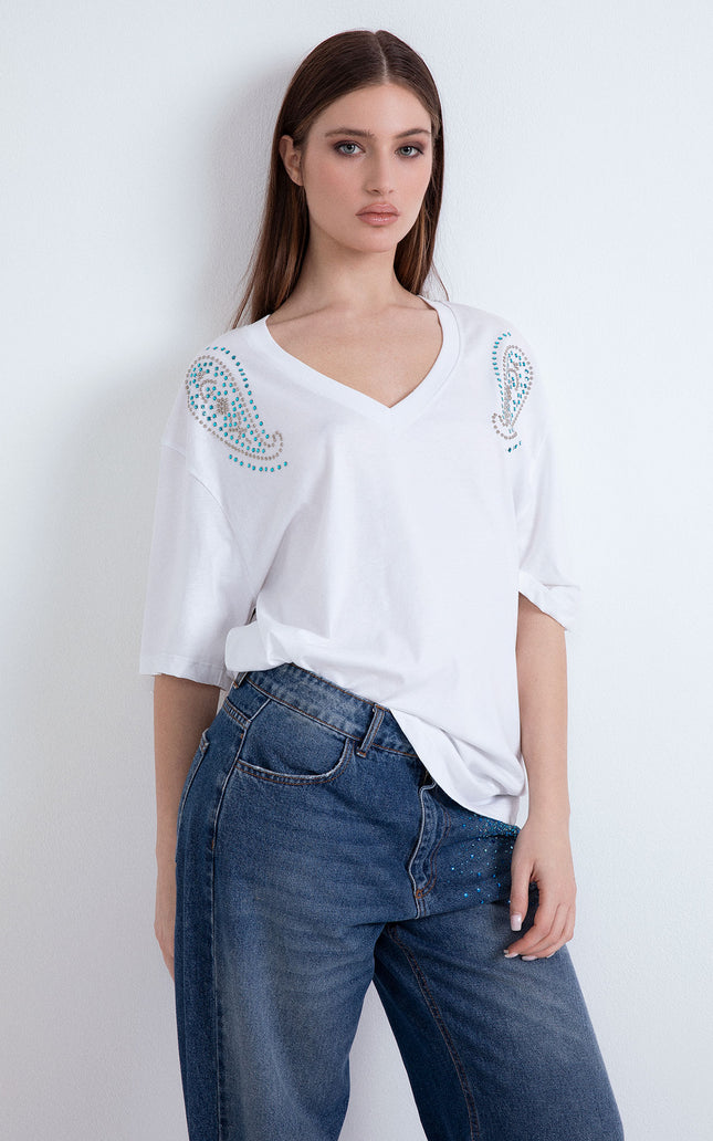 Modella indossa la t-shirt oversize bianca Dubai Doodles con scollo a V e borchie.