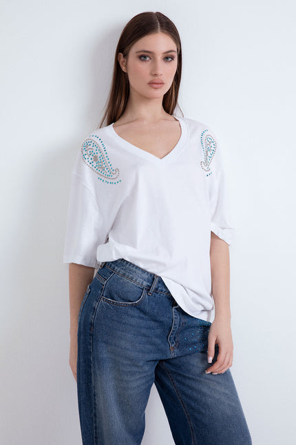 Modella indossa la t-shirt oversize bianca Dubai Doodles con scollo a V e borchie.