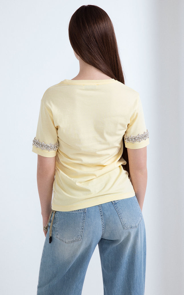 Vista posteriore di t-shirt gialla in cotone con applicazione di strass sulle maniche corte.