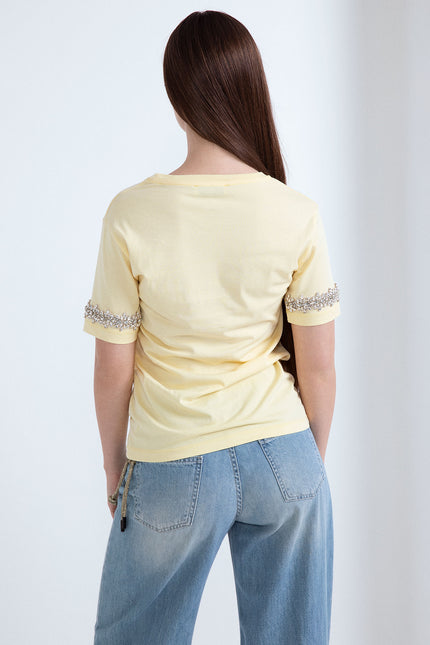 Vista posteriore di t-shirt gialla in cotone con applicazione di strass sulle maniche corte.