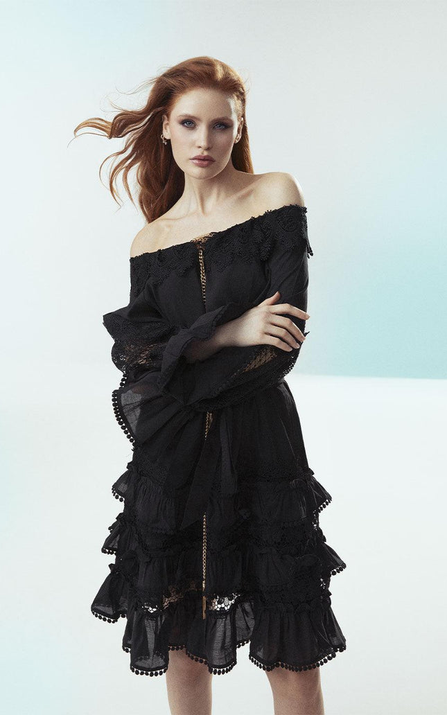 Woman in off-shoulder black lace dress with ruffle details, fashionable look