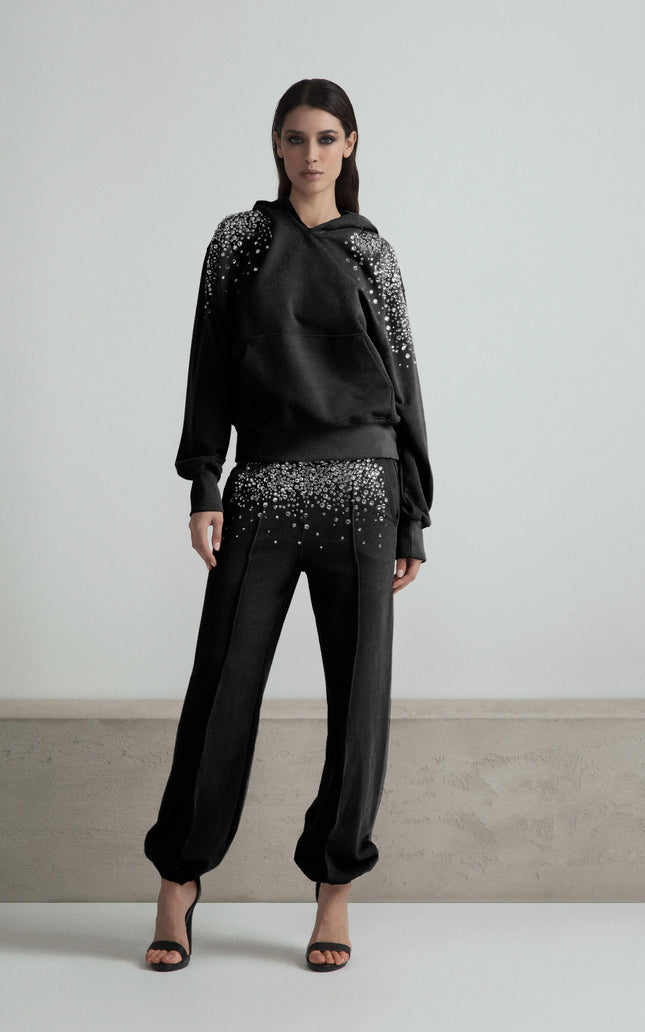 Woman wearing black embellished hoodie and pants set, modern fashion, white background