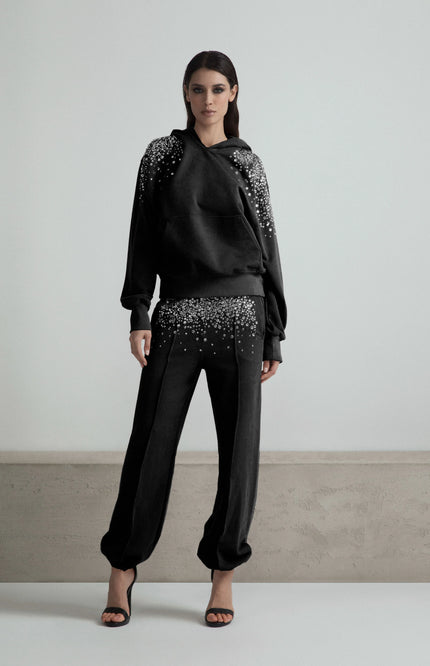 Woman wearing black embellished hoodie and pants set, modern fashion, white background