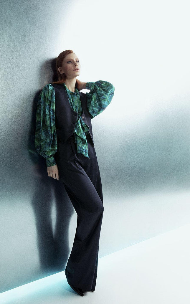 Woman in modern green print blouse with black vest and wide-leg pants, fashion shoot