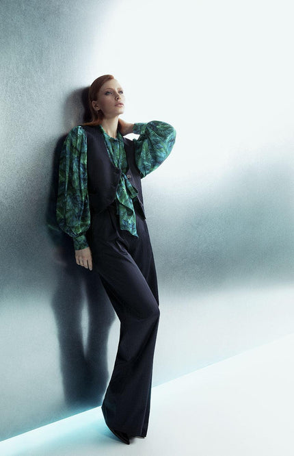 Woman in modern green print blouse with black vest and wide-leg pants, fashion shoot