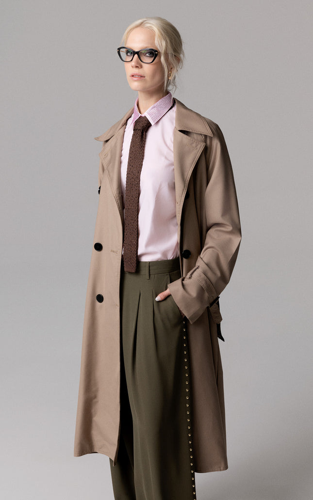 Outfit di alta moda femminile abbinato a cravatta marrone decorata e trench coat.