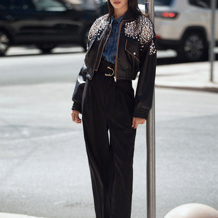 Woman in high-waisted black pants and embellished black jacket, street style fashion
