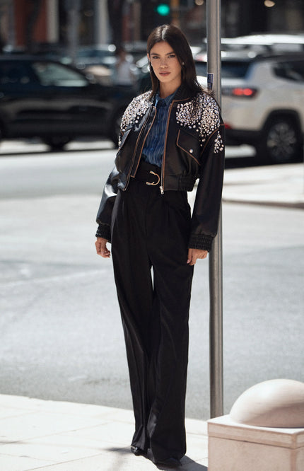 Woman in high-waisted black pants and embellished black jacket, street style fashion