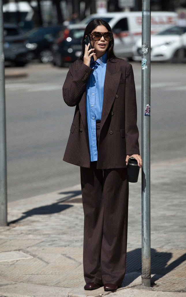 Woman wearing brown pinstripe suit and blue shirt, street style fashion