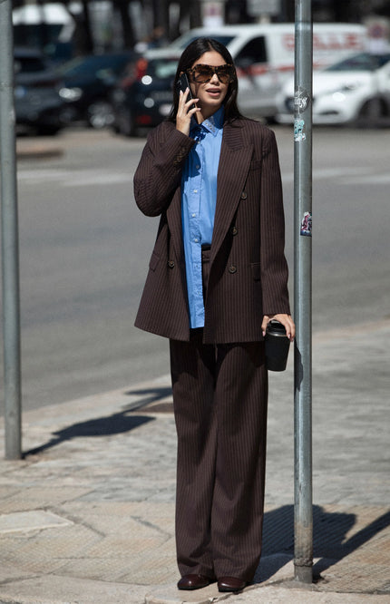 Woman wearing brown pinstripe suit and blue shirt, street style fashion